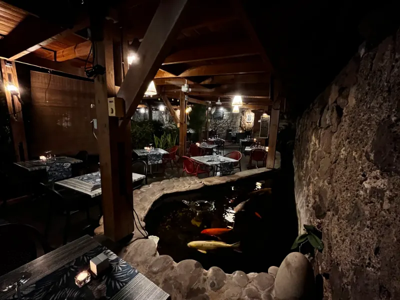 Le bassin et les tables du patio le soir, sous les lanternes.