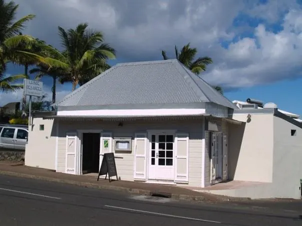 La façade blanche du restaurant sur l'avenue, sous les palmiers.