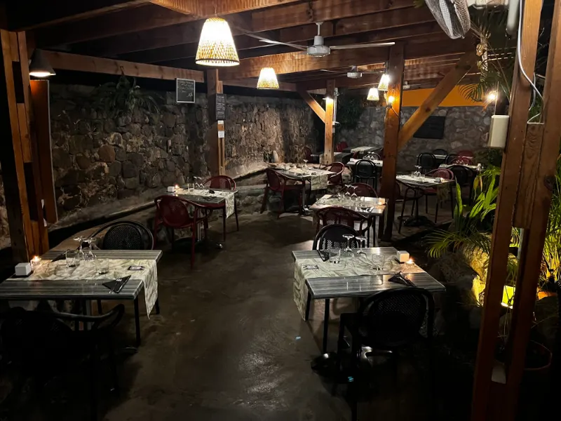 La terrasse couverte le soir, tables dressées sous les bois et les lanternes.